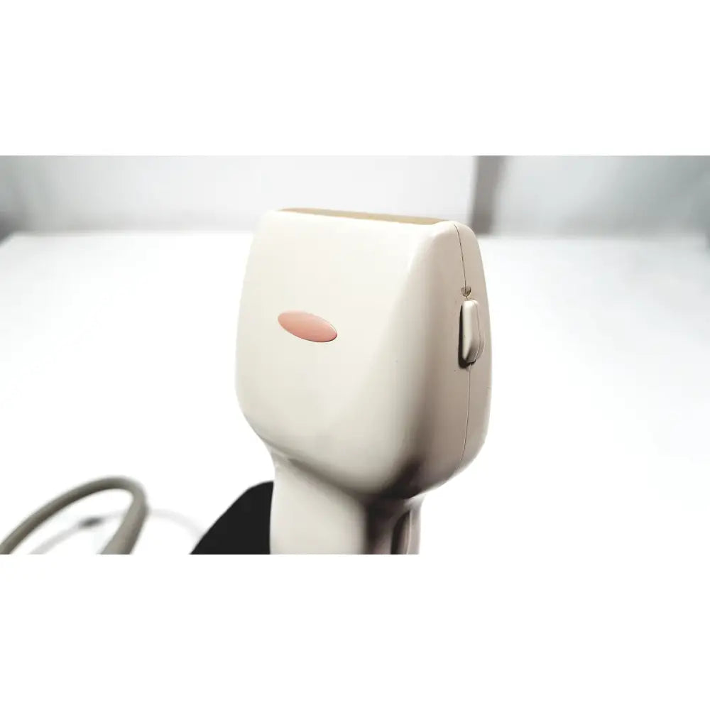 Cream-colored plastic epilator with pink power button and silver switch beside GE Medical Systems ultrasound convex array transducer