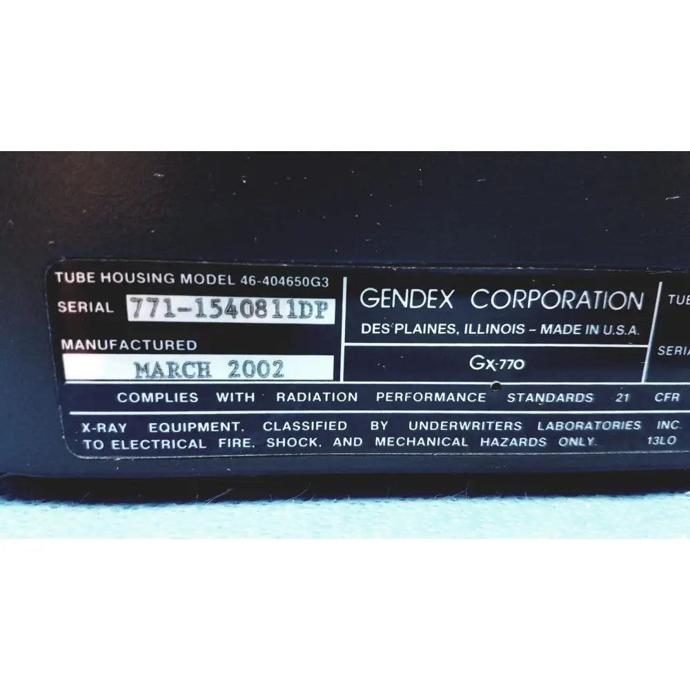 Black plastic label with white text on gendex 770 tube head detailing model and manufacturer for imaging equipment reuse medical