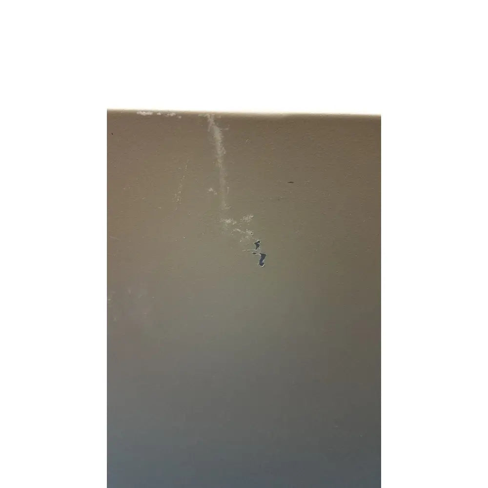 A small dark crack runs vertically on the beige surface of a general purpose medium steel nema 1 enclosure wall