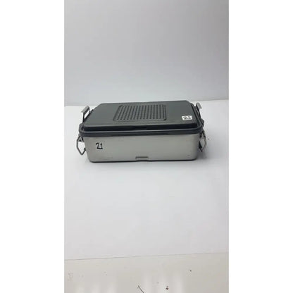 Gray and silver metal genesis solid brass sterilization container with perforated lid and side handles for surgical instruments