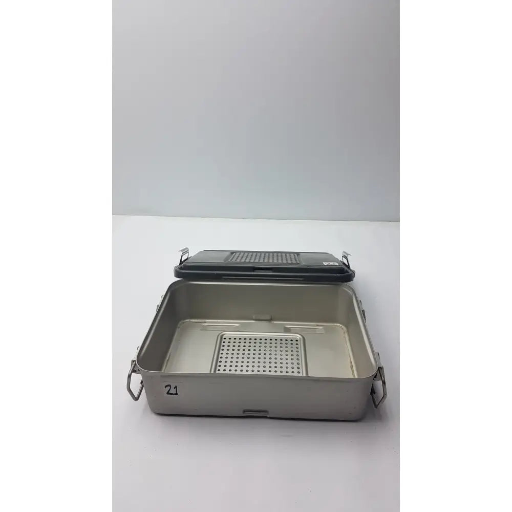 Genesis solid brass sterilization container with silver stainless steel tray, black perforated lid, and side handles