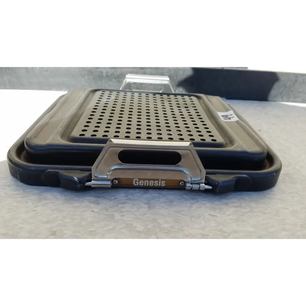 Black plastic genesis sterilization container half lid with perforated metal insert and silver handle bearing genesis brand name