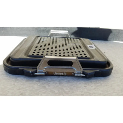 Black plastic genesis sterilization container half lid with perforated metal insert and silver handle bearing genesis brand name