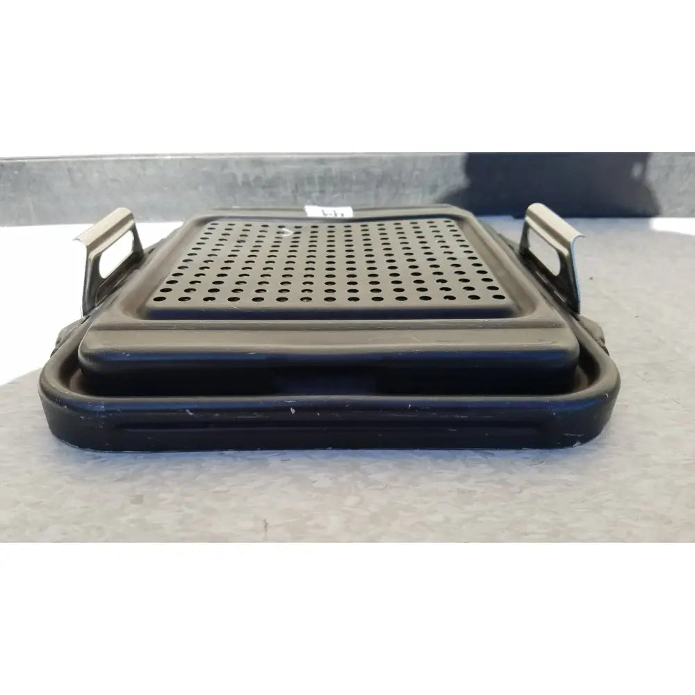 Black plastic genesis sterilization container half lid with perforated surface and metal handles for secure grip