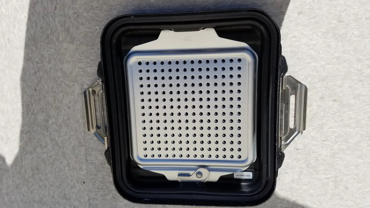 Silver perforated grill insert inside black rugged genesis sterilization container half lid with metallic latches