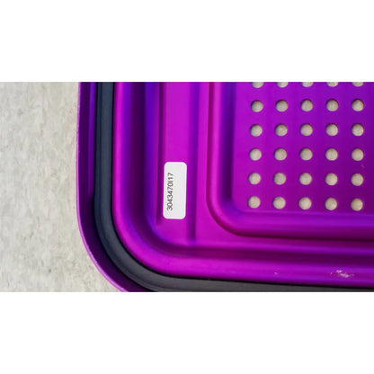 Purple plastic genesis sterilization container half lid with black rim and circular perforations for sterile storage