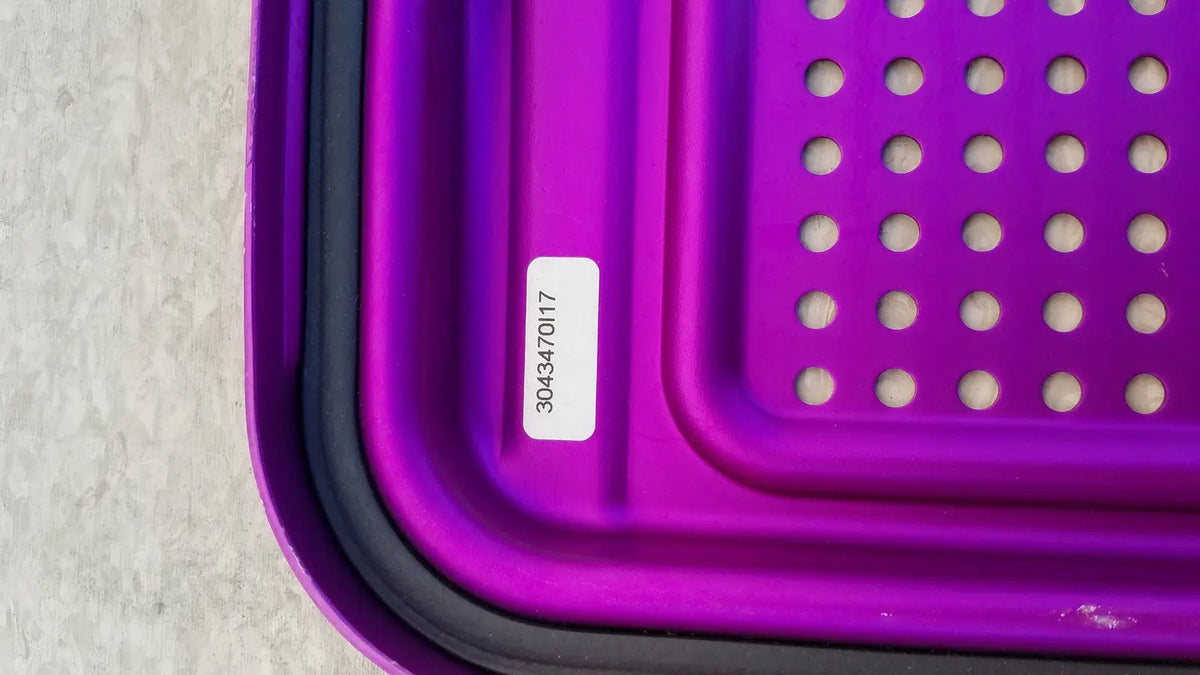 Purple plastic genesis sterilization container half lid with black rim and circular perforations for sterile storage