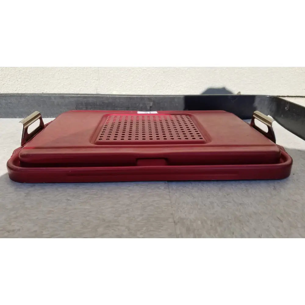 Red plastic genesis sterilization container half lid with perforated surface and metallic handles for secure closure