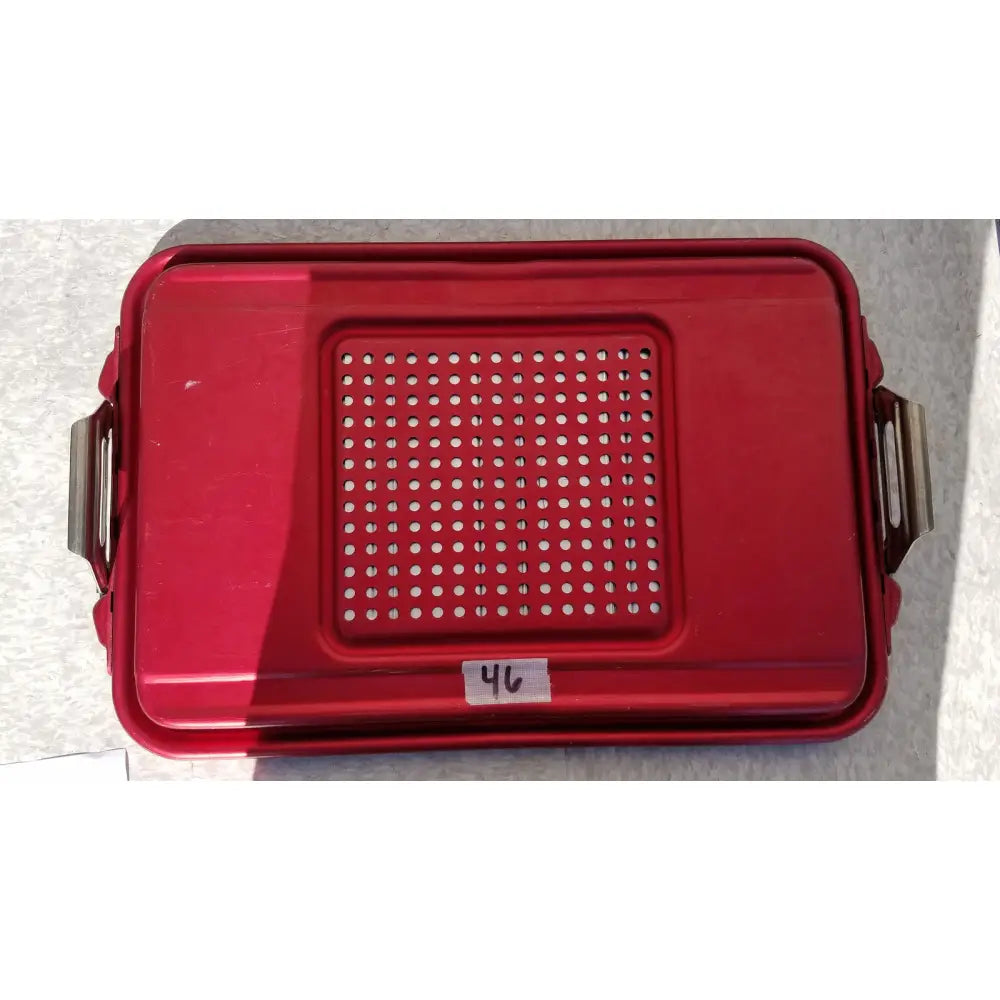 Red plastic genesis sterilization container half lid with perforated design and metal side handles for secure storage