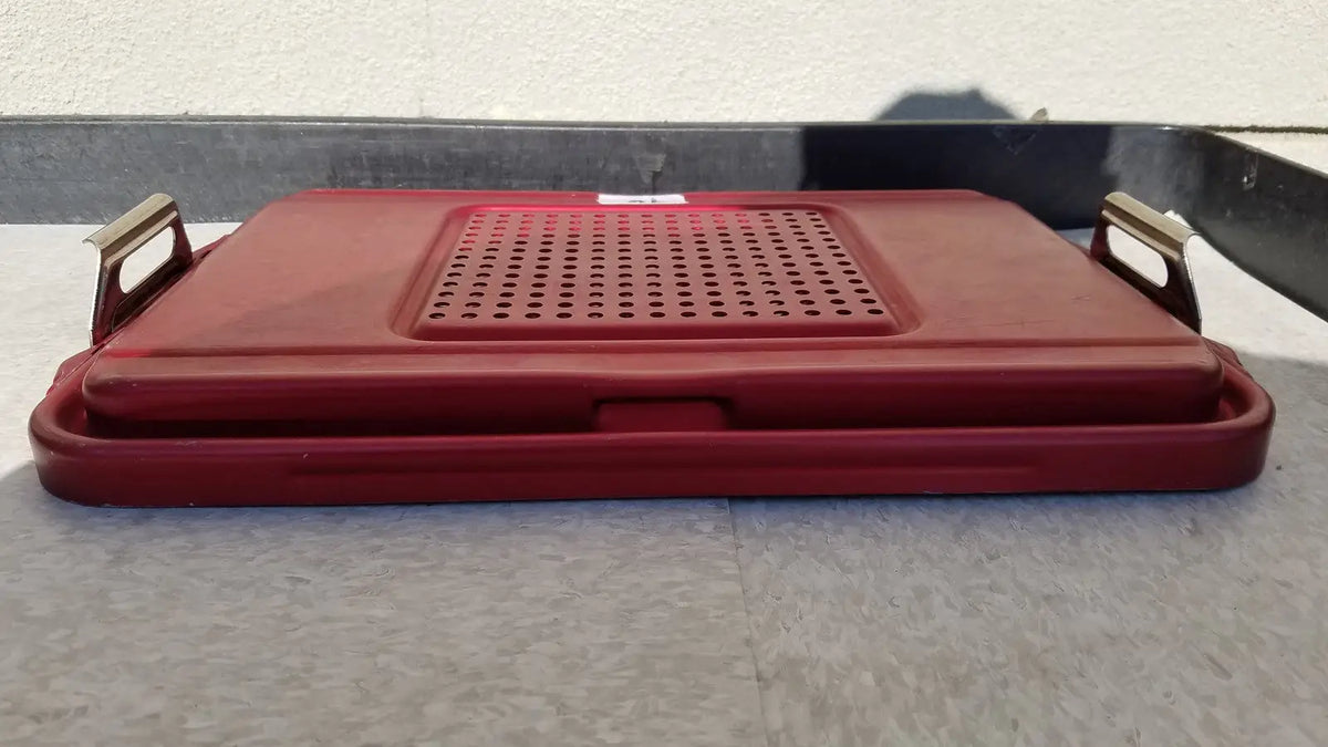 Red plastic genesis sterilization container half lid with perforated surface and metallic handles for secure closure