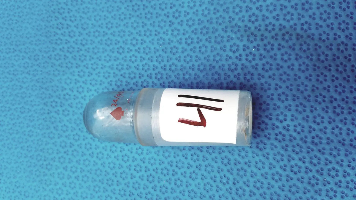 Clear glass vial with rounded cap and white label marked 14 featuring faint red hearts in a glass flask stopper set