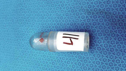 Clear glass vial with rounded cap and white label marked 14 featuring faint red hearts in a glass flask stopper set