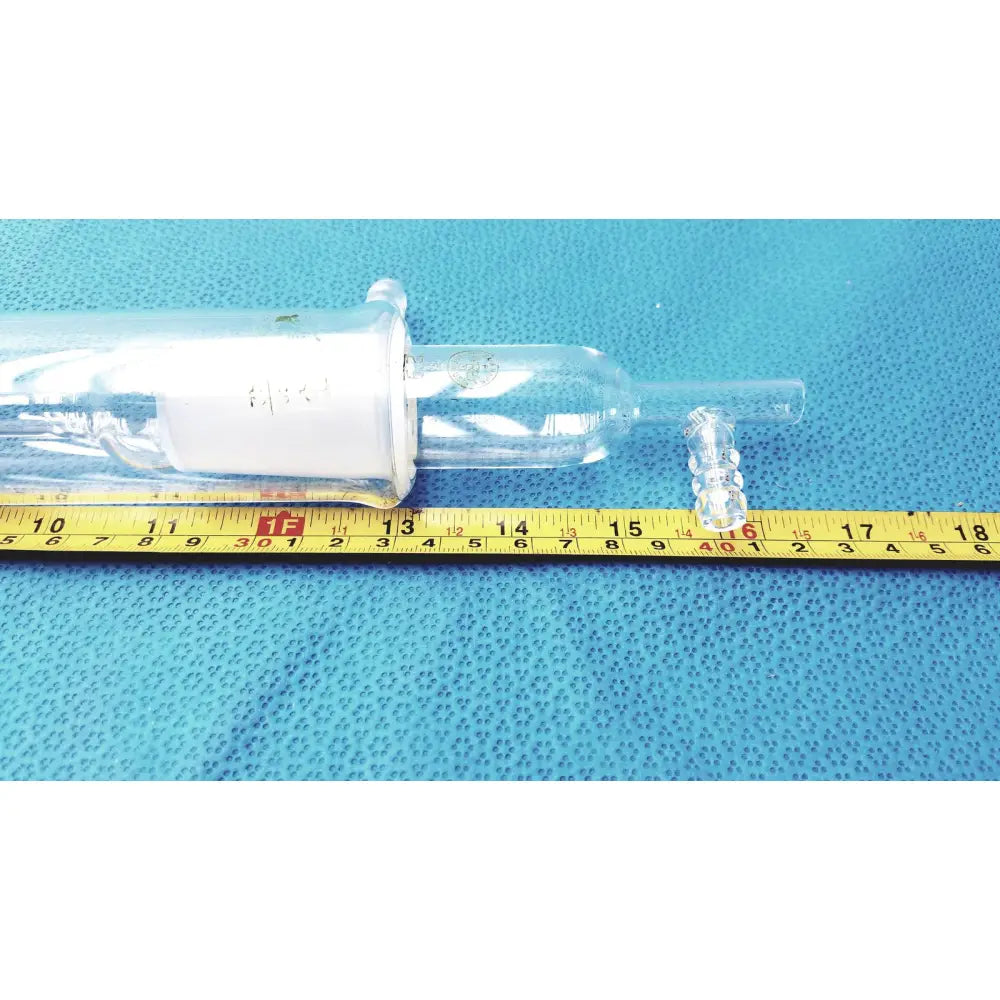 Clear glass liebig condenser with white cylindrical component and transparent tubing ends borosilicate labware for distillation
