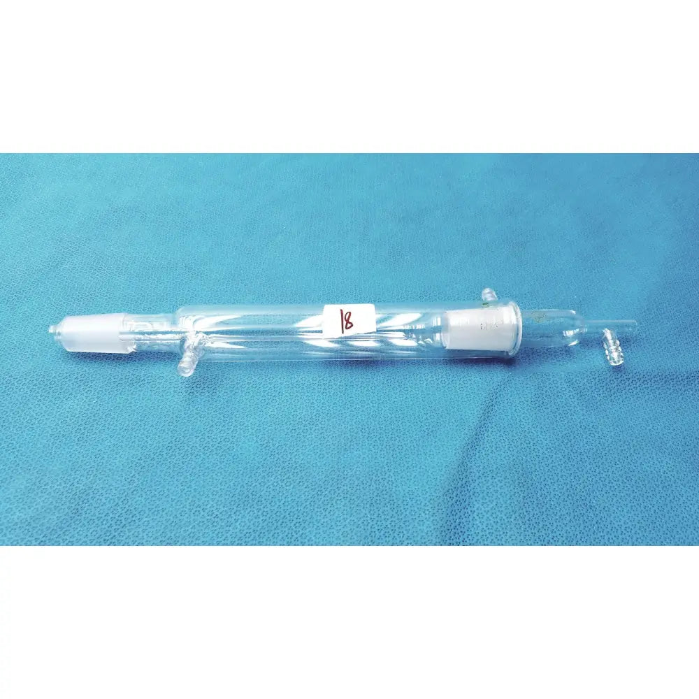 Clear glass liebig condenser with white ceramic fittings and red 18 label borosilicate labware for distillation