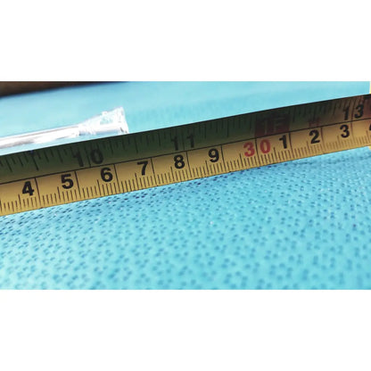 Yellow metal ruler with black and red markings on blue surface near a glass straight bore ground glass valve stopcock