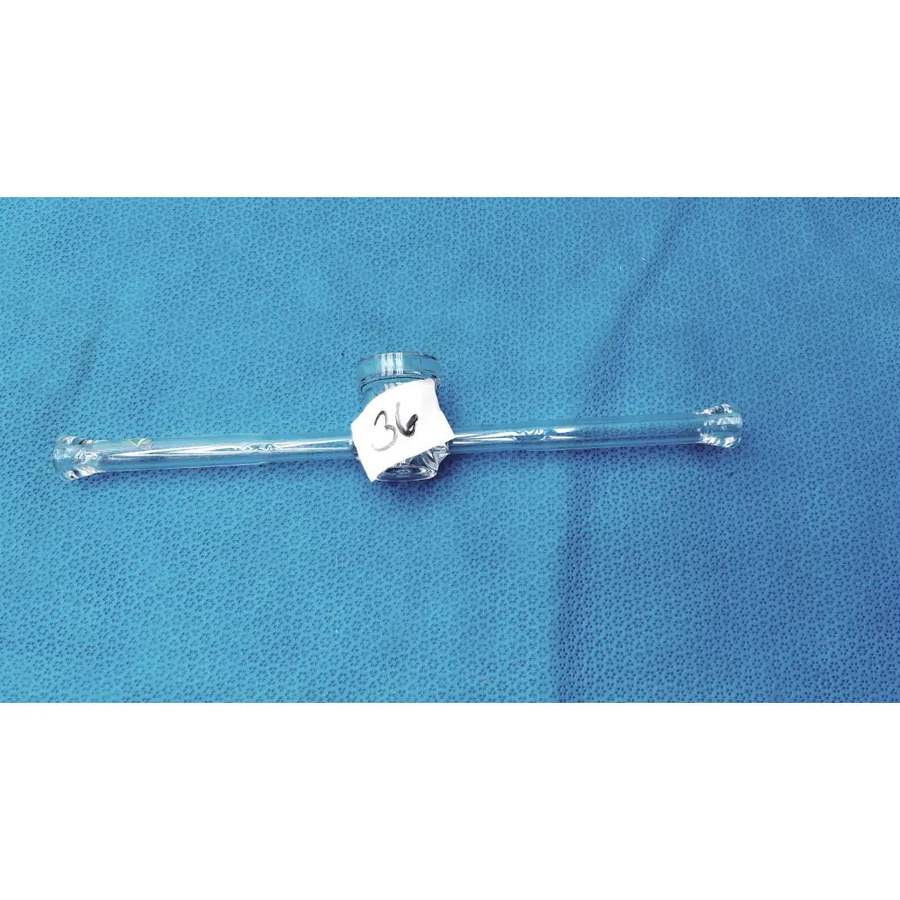 Clear glass straight bore stopcock with central cylindrical component and ground glass valve labeled 34 for lab glassware