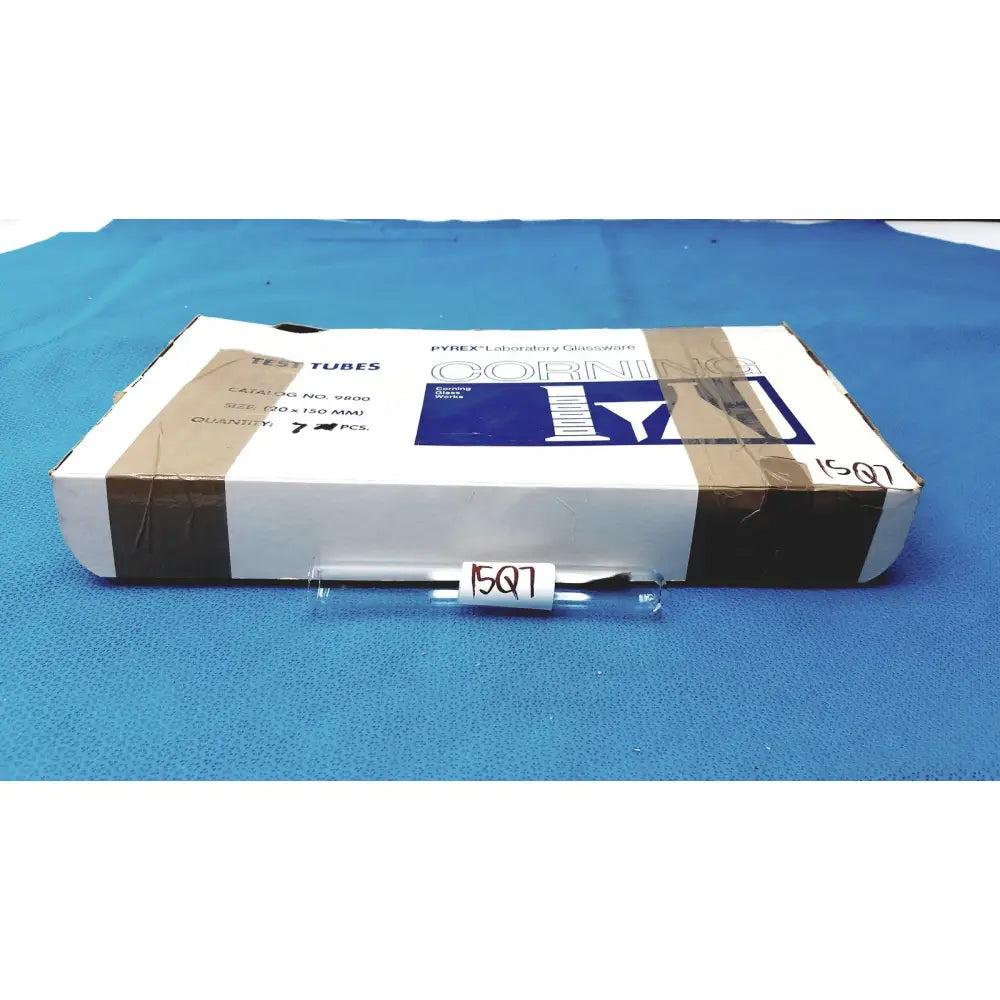 Clear glass borosilicate test tube 25x150mm with white label 1507 resting in front of its packaging