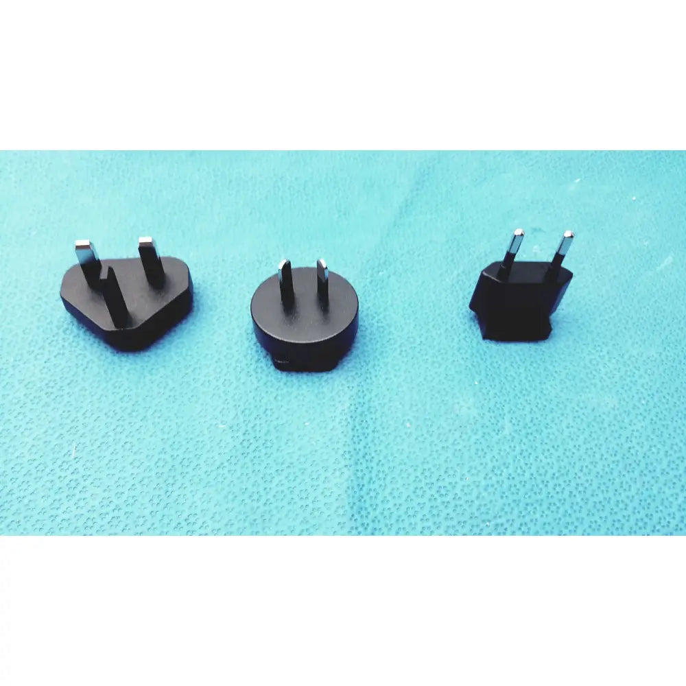 Three black travel plug adapters with metallic prongs for international use compatible with glidescope video monitor an162878