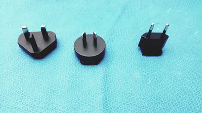Three black travel plug adapters with metallic prongs for international use compatible with glidescope video monitor an162878