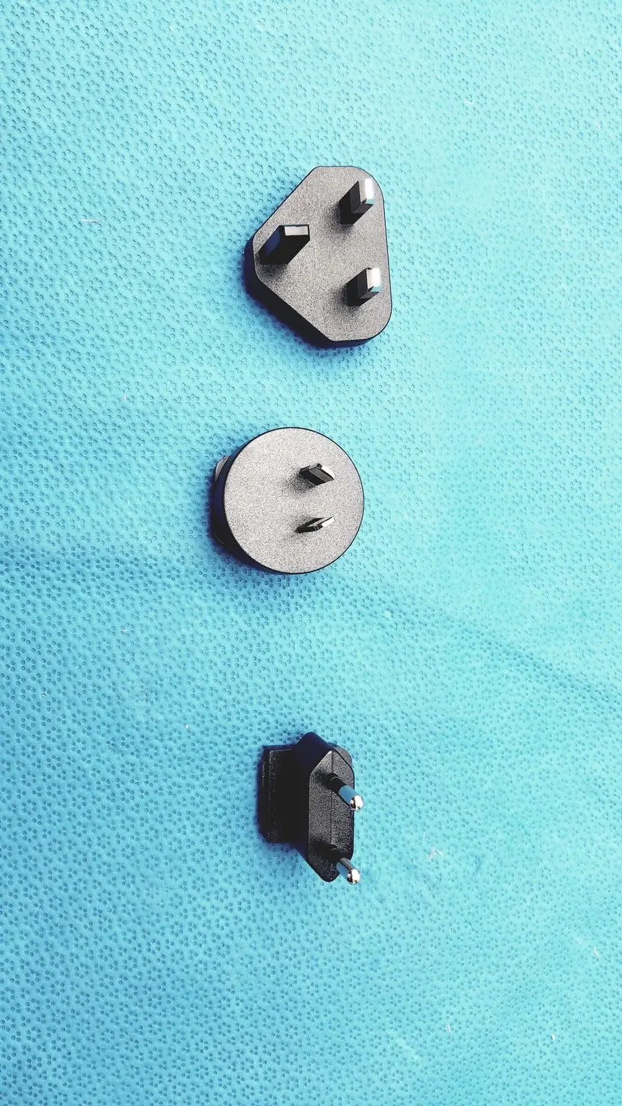Three distinct metallic and black plastic power plugs with varying pin configurations on the glidescope video monitor an162878