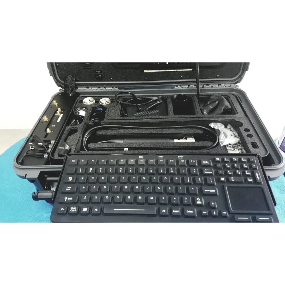 Black keyboard with integrated touchpad in front of rugged case containing tools in globalmed telemedicine kit riester
