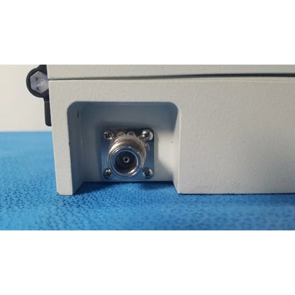 Silver n-type coaxial connector mounted on white plastic housing with screws on gms general microwave c/f-band receiver back side