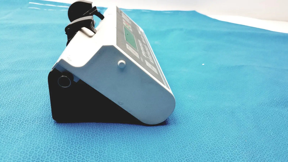White and black Graseby 3100 syringe delivery device clean unit with small circular button for precise medical use