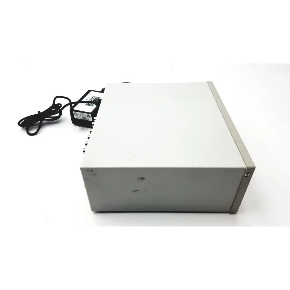 Gray rectangular grass 15lt physiodata 15a54 quad amplifier system with black power adapter and cord nearby
