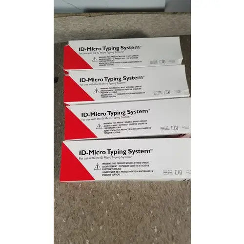 Stacked white and red cardboard boxes of grifols cards featuring dilution trays and evaporation caps on a carpeted floor