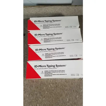 Stacked white and red cardboard boxes of grifols cards featuring dilution trays and evaporation caps on a carpeted floor