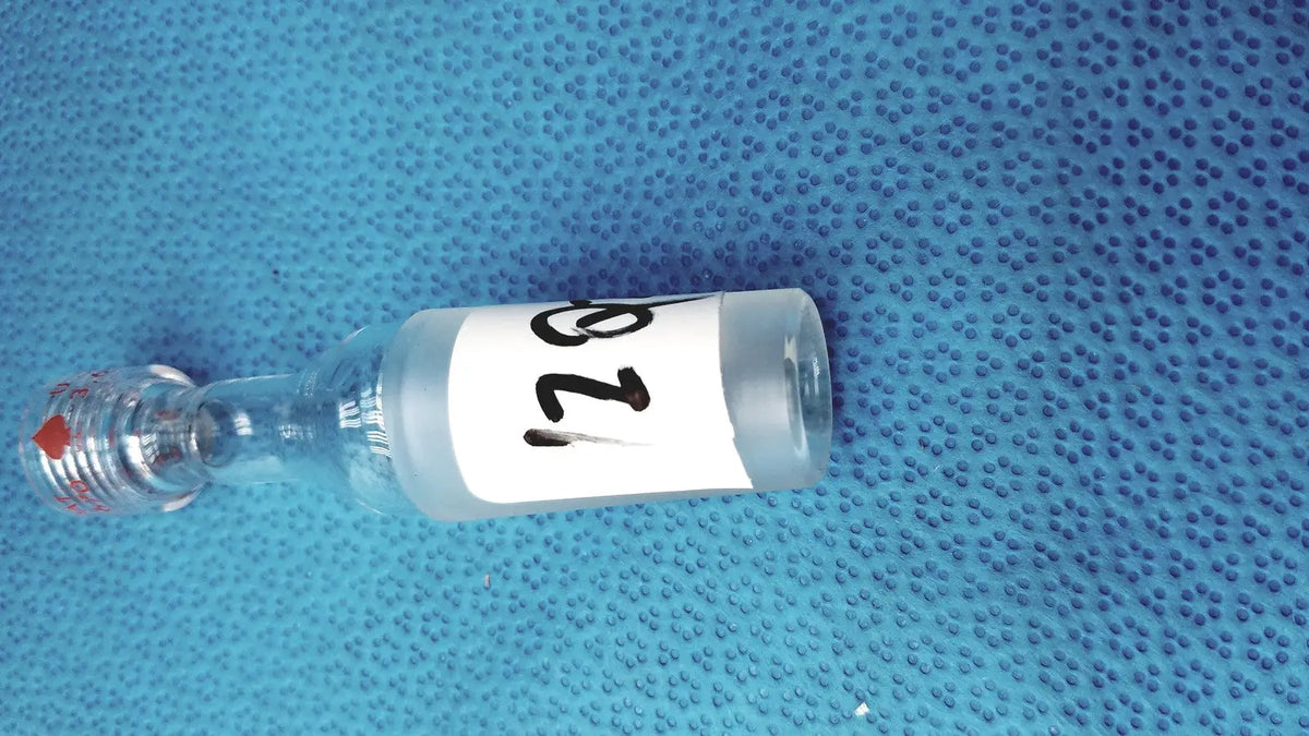 Clear glass vial with white label number 128 and red-tipped stopper used with ground glass cone rubber tubing connector lab joint