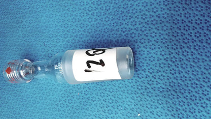 Clear glass vial with white label number 128 and red-tipped stopper used with ground glass cone rubber tubing connector lab joint