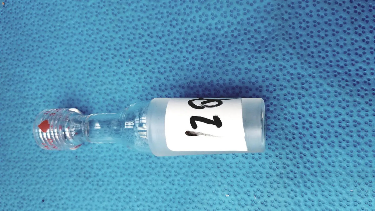 Clear glass vial with white label number 128 and red cap mark illustrating ground glass cone rubber tubing connector lab joint