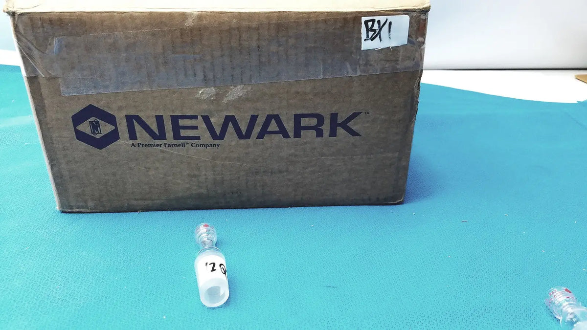 A clear plastic vial with silver cap and label marked 20 on blue surface for ground glass cone rubber tubing connector lab use