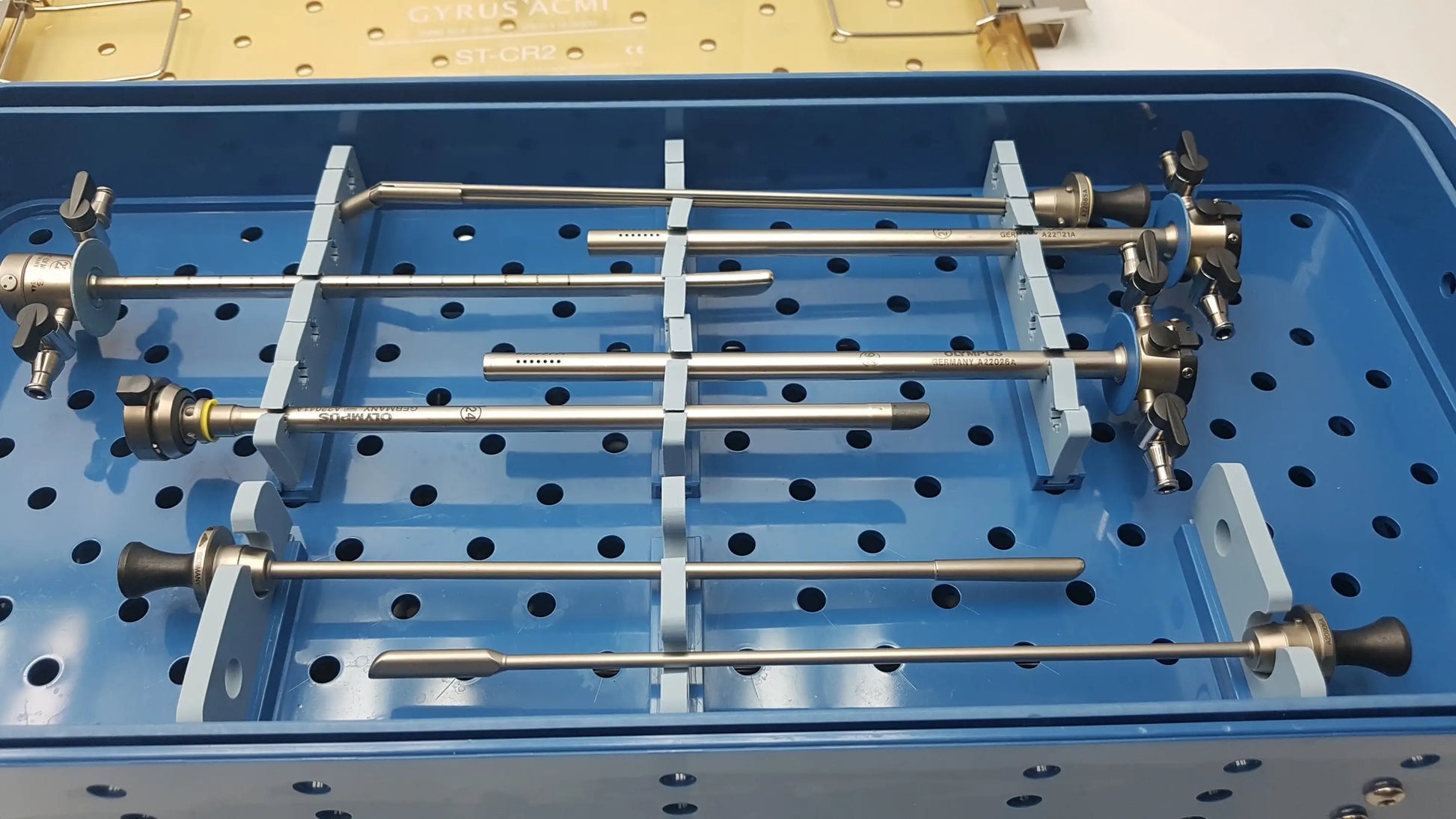 Gyrus acmi endoscopic surgical instrument set with metallic shafts and black handles in blue sterilization tray