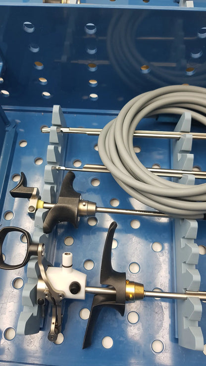 A coiled gray medical cable with metallic connectors on a blue tray in the gyrus acmi endoscopic surgical instrument set