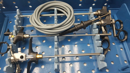 Gray coiled surgical instrument with black and metallic components in blue perforated tray from gyrus acmi instrument set