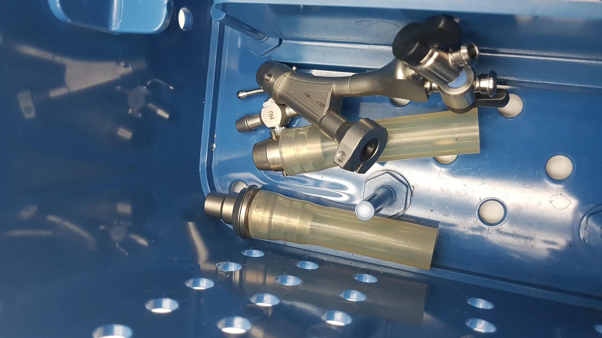 Gyrus acmi endoscopic surgical instrument set with silver and brass components and black fittings in blue metal tray