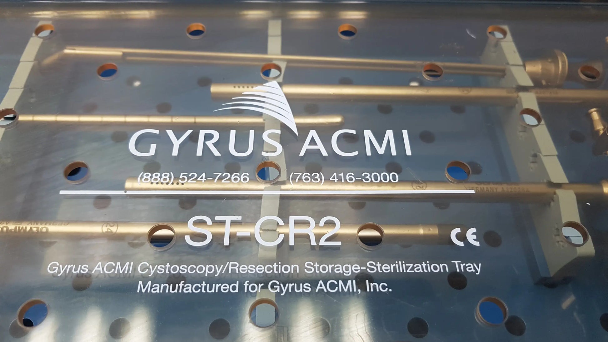 Silver metallic GYRUS ACMI surgical instrument set tray with gold cylindrical rods labeled for cystoscopy and resection use