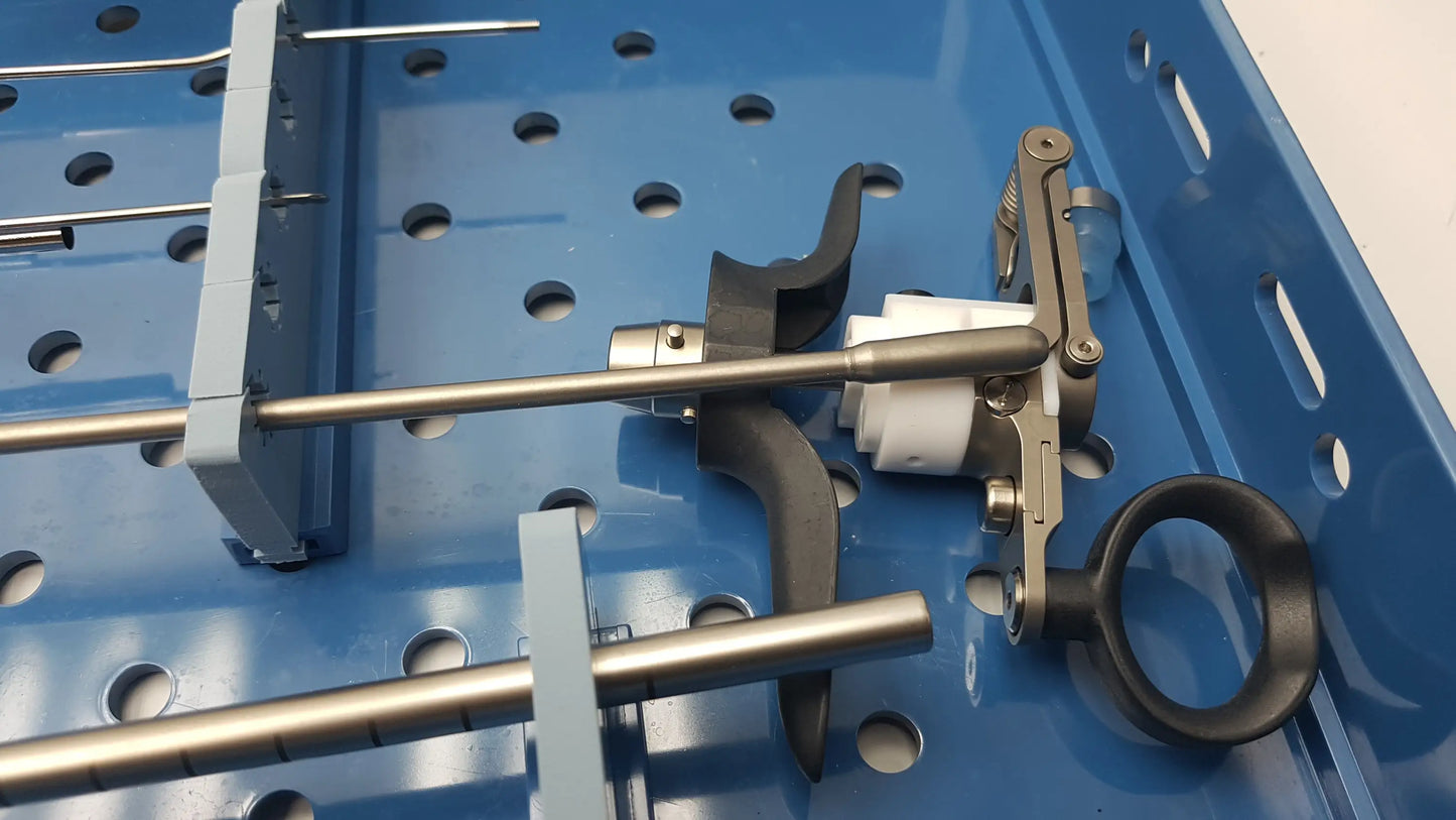 Metallic surgical instrument with black ergonomic handle resting on a blue perforated endoscope sterilization tray with olympus a3551 urethrotome sheath