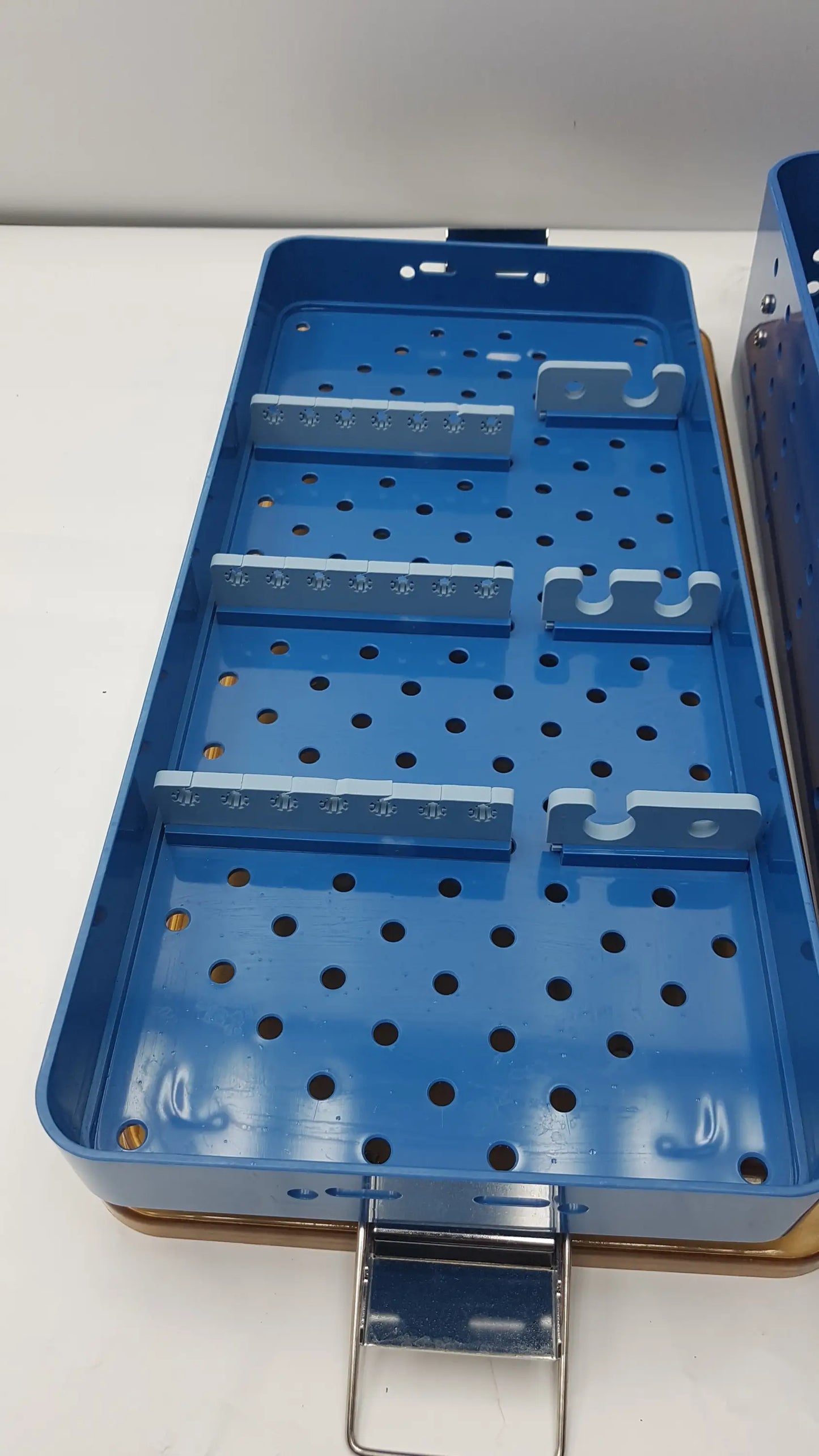 Blue metal gyrus acmi endoscope storage tray with perforated surface and adjustable gray plastic dividers for sterilization