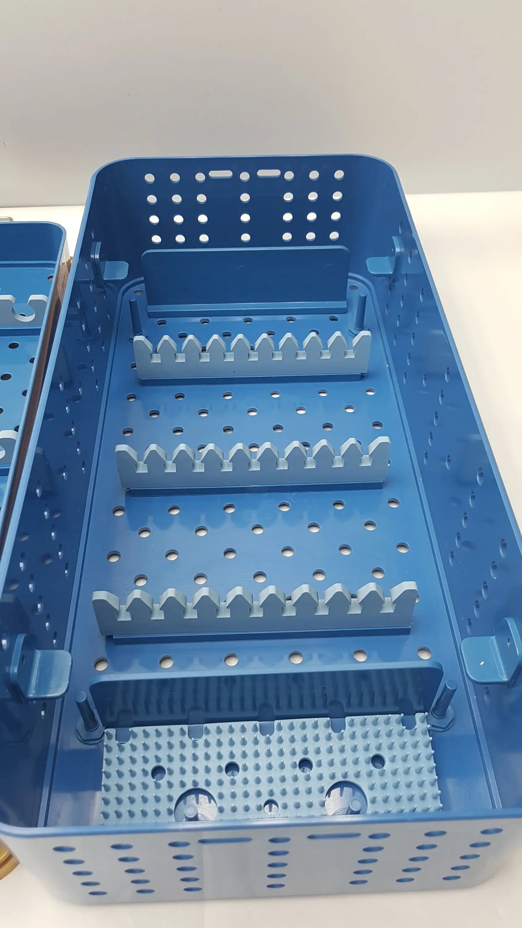 Blue plastic gyrus acmi endoscope storage tray with perforated sides and tiered tooth-like dividers for sterilization