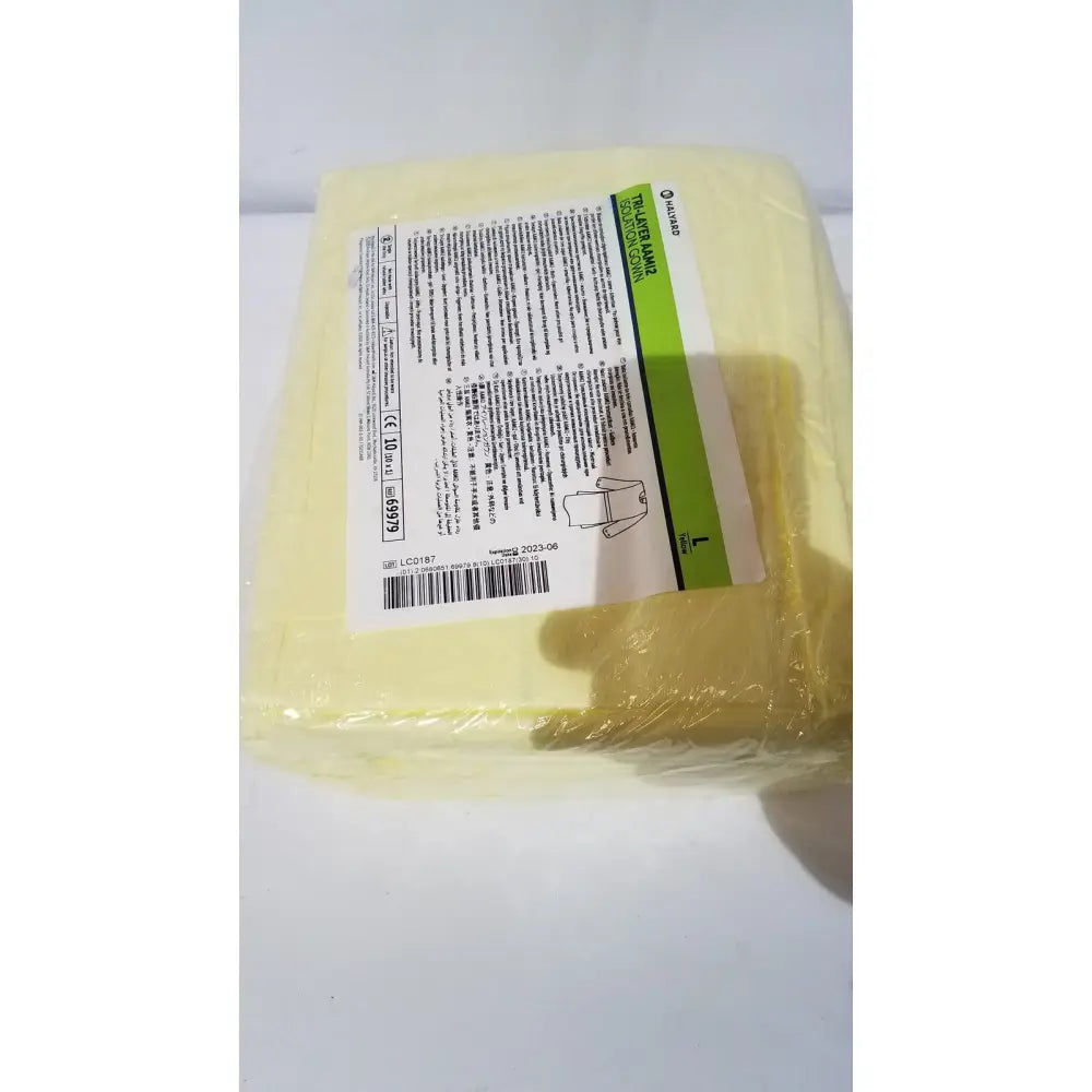 Yellow plastic hand warmer wrapped in clear plastic with green and white label alongside halyard tri-layer disposable gown blue