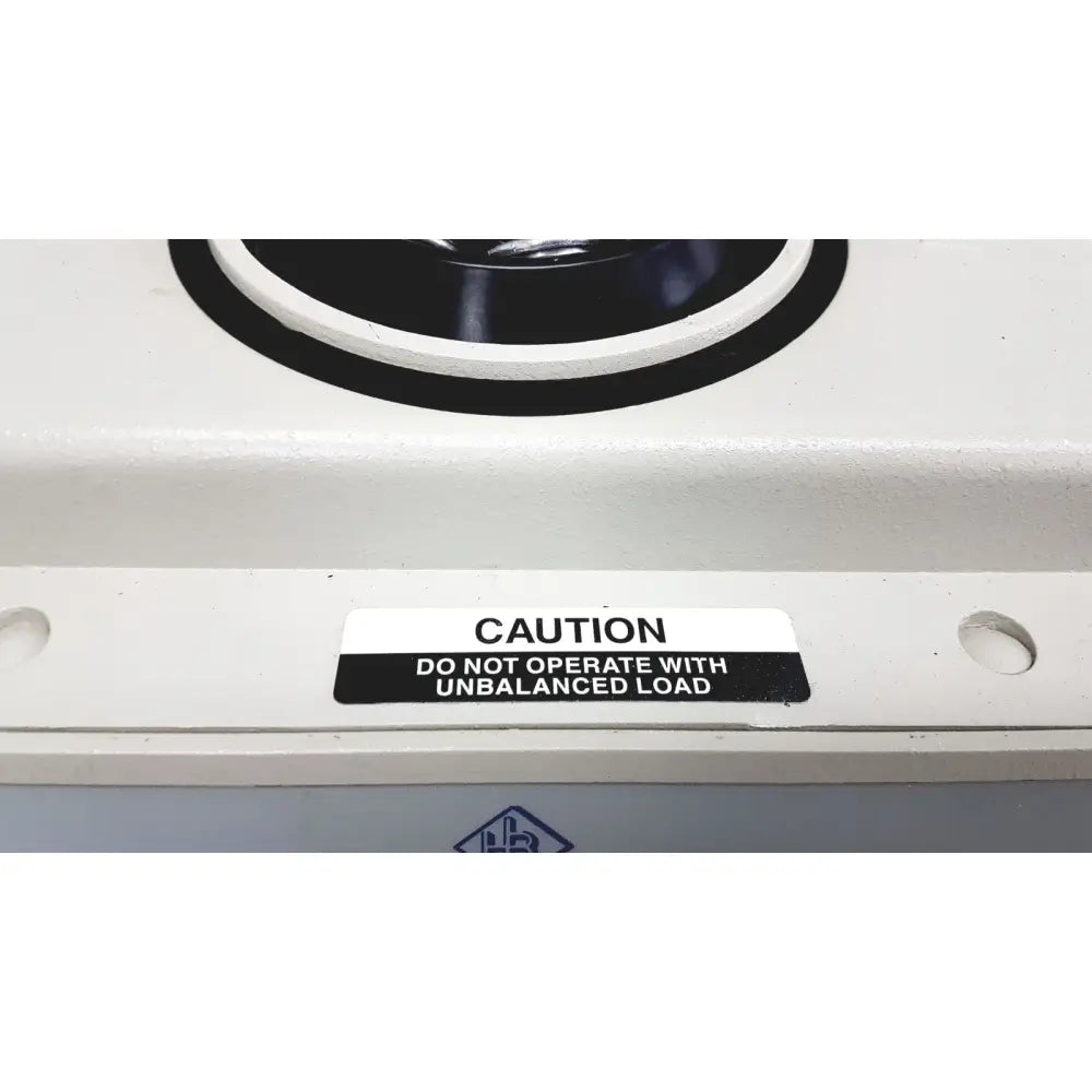 White industrial hamilton bell vanguard v6500 centrifuge with black circular component and caution label on unbalanced load operation