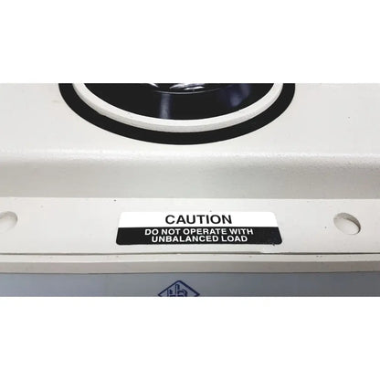 White industrial hamilton bell vanguard v6500 centrifuge with black circular component and caution label on unbalanced load operation
