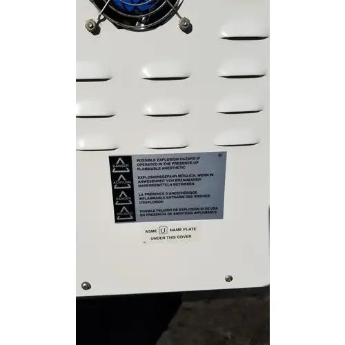 White industrial air compressor with blue circular component and warning label in harvey sterilemax st75935 model