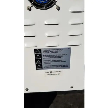White industrial air compressor with blue circular component and warning label in harvey sterilemax st75935 model