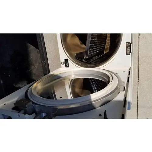 The stainless steel drum of the white harvey sterilemax st75935 front-loading washing machine is open showing its interior components