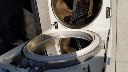 The stainless steel drum of the white harvey sterilemax st75935 front-loading washing machine is open showing its interior components