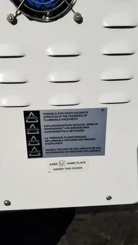 White industrial air compressor with blue circular component and warning label in harvey sterilemax st75935 model